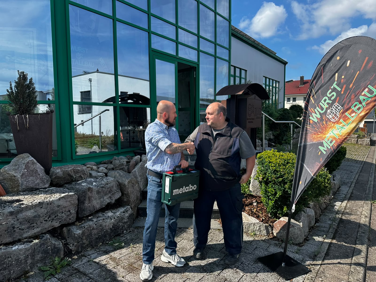 Übergabe des Metabo-Werkzeugkoffers an Herrn Engele vor dem Firmengebäude von Wurst Metallbau.